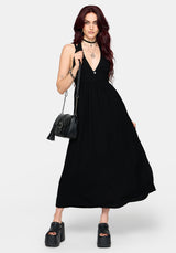 Woman wearing a long black dress holding a black handbag on a white background