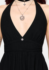 Black halterneck dress with a deep neckline and silver jewelry on a neutral background