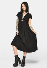 Woman wearing a black dress with cut-out design and short sleeves on a white background