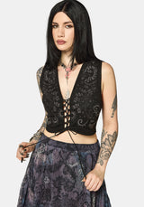 Woman wearing a black lace-up top with floral patterns on a white background