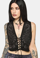 Woman wearing a black lace-up top with intricate designs on a white background