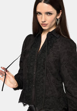 Woman wearing a black lace detail blouse against a white background