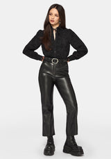Woman wearing a black long sleeve lace detail blouse with a plain background