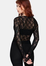 Woman wearing a black long sleeve lace top against a white background