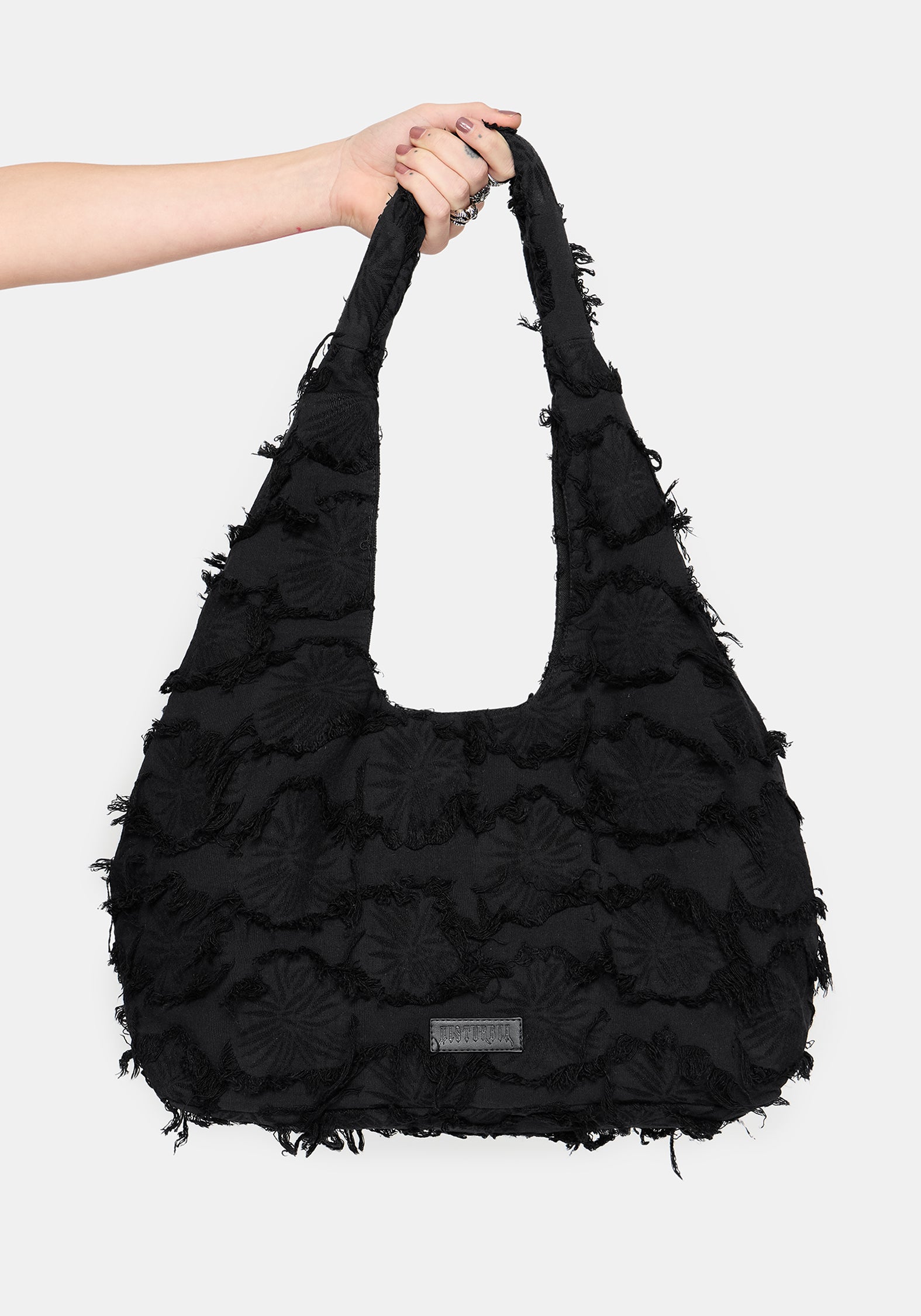 Black ruffled handbag held by a person against a white background