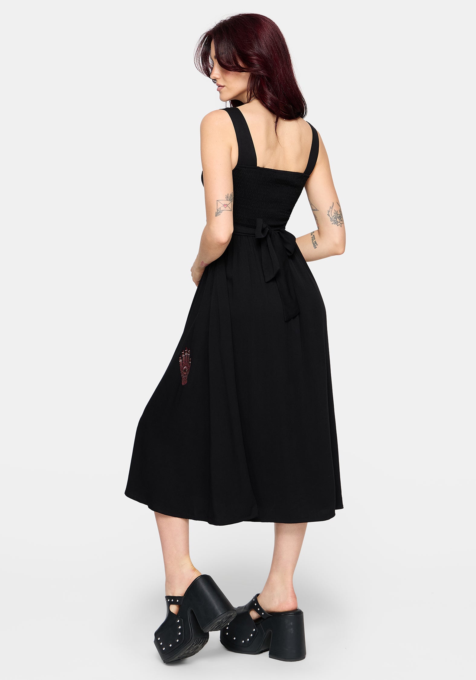 Woman wearing a black dress with a tie waist on a white background