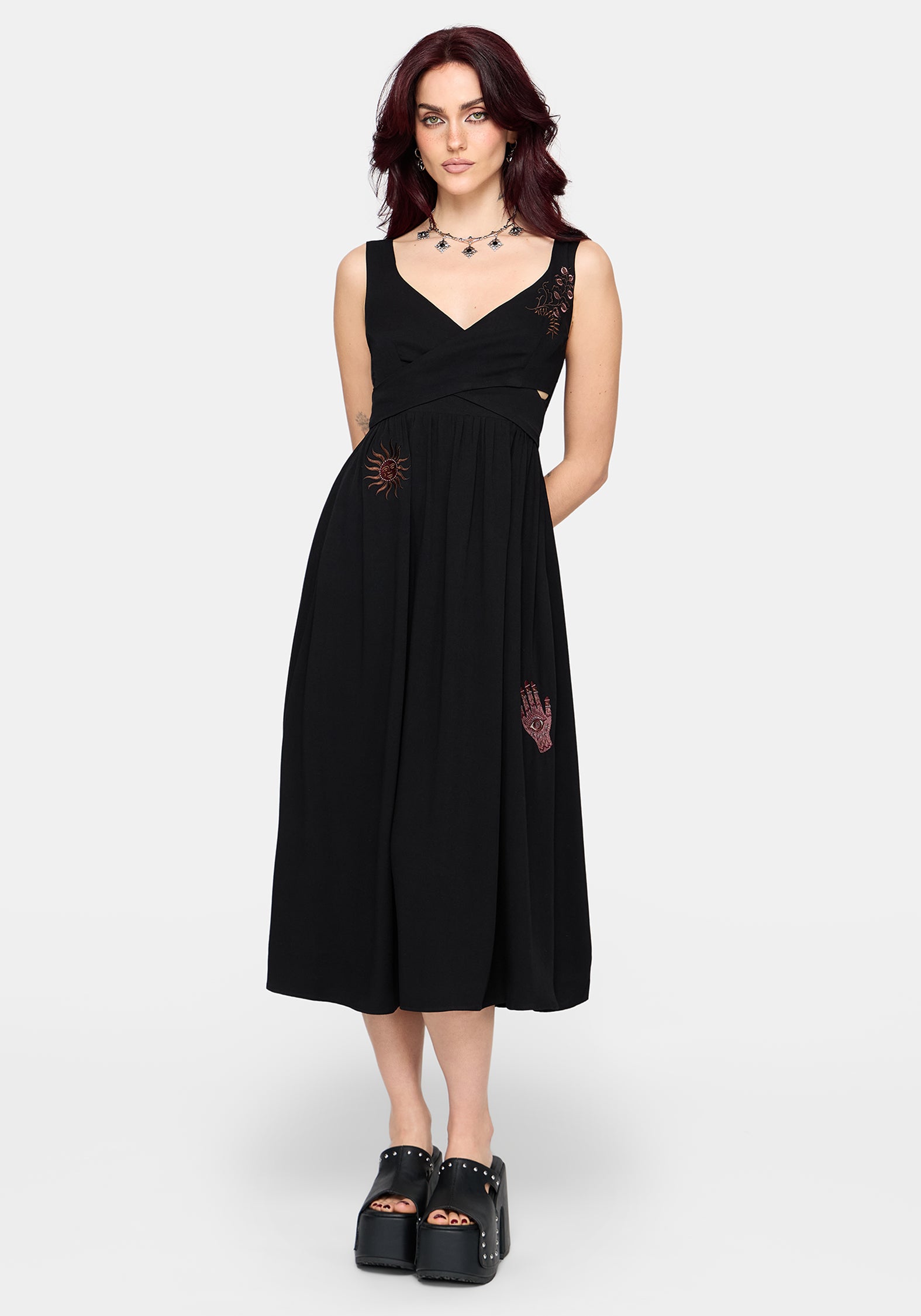 Woman wearing a black dress with cut-out design and embroidered details on a white background