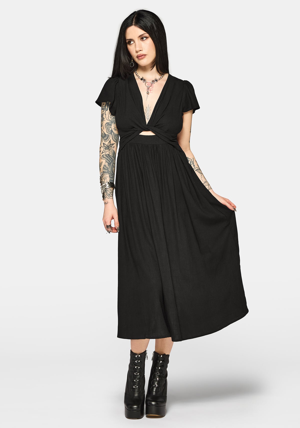 Woman wearing a black dress with cut-out design and short sleeves on a white background