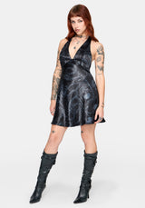 Woman wearing a black satin snake printed mini dress against a white background