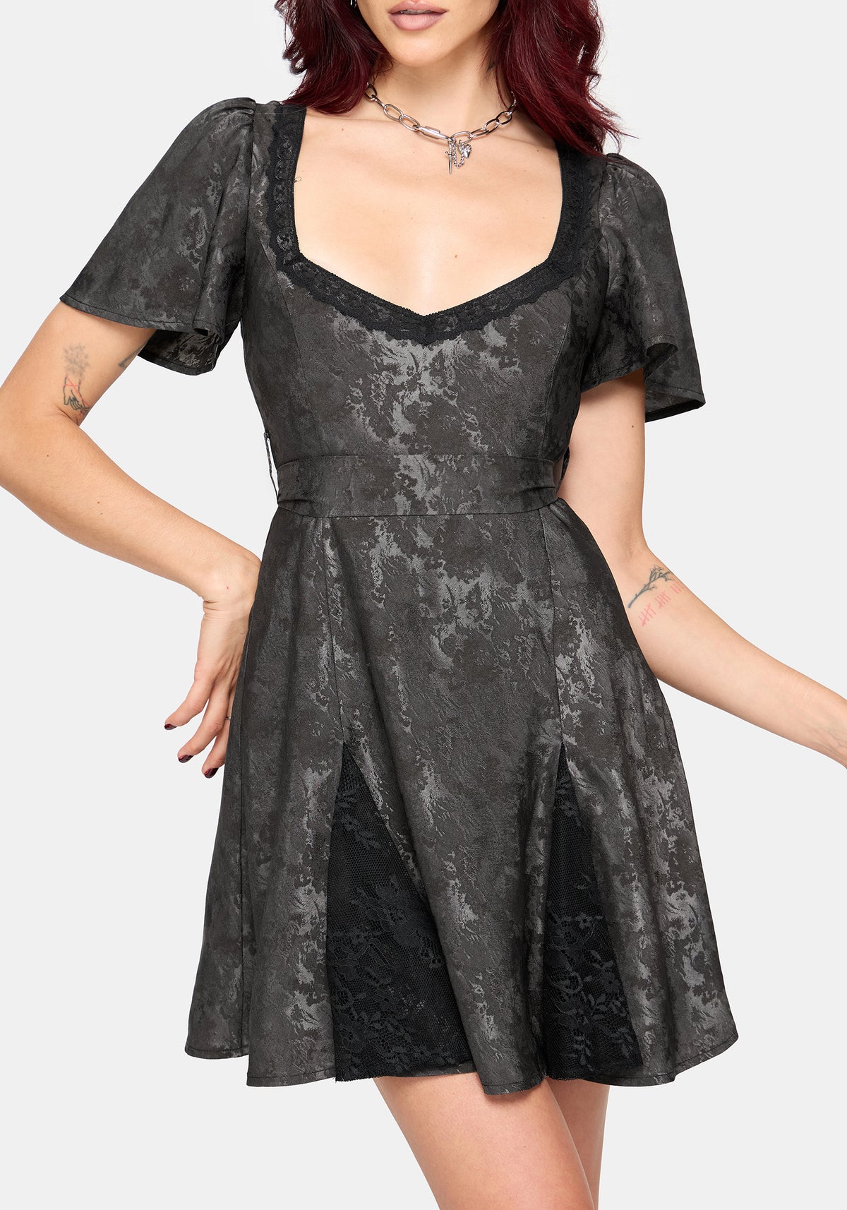 A woman wearing a short grey mini dress with a smocked bodice, puff sleeves, and a square neckline, shown against a light gray studio background.