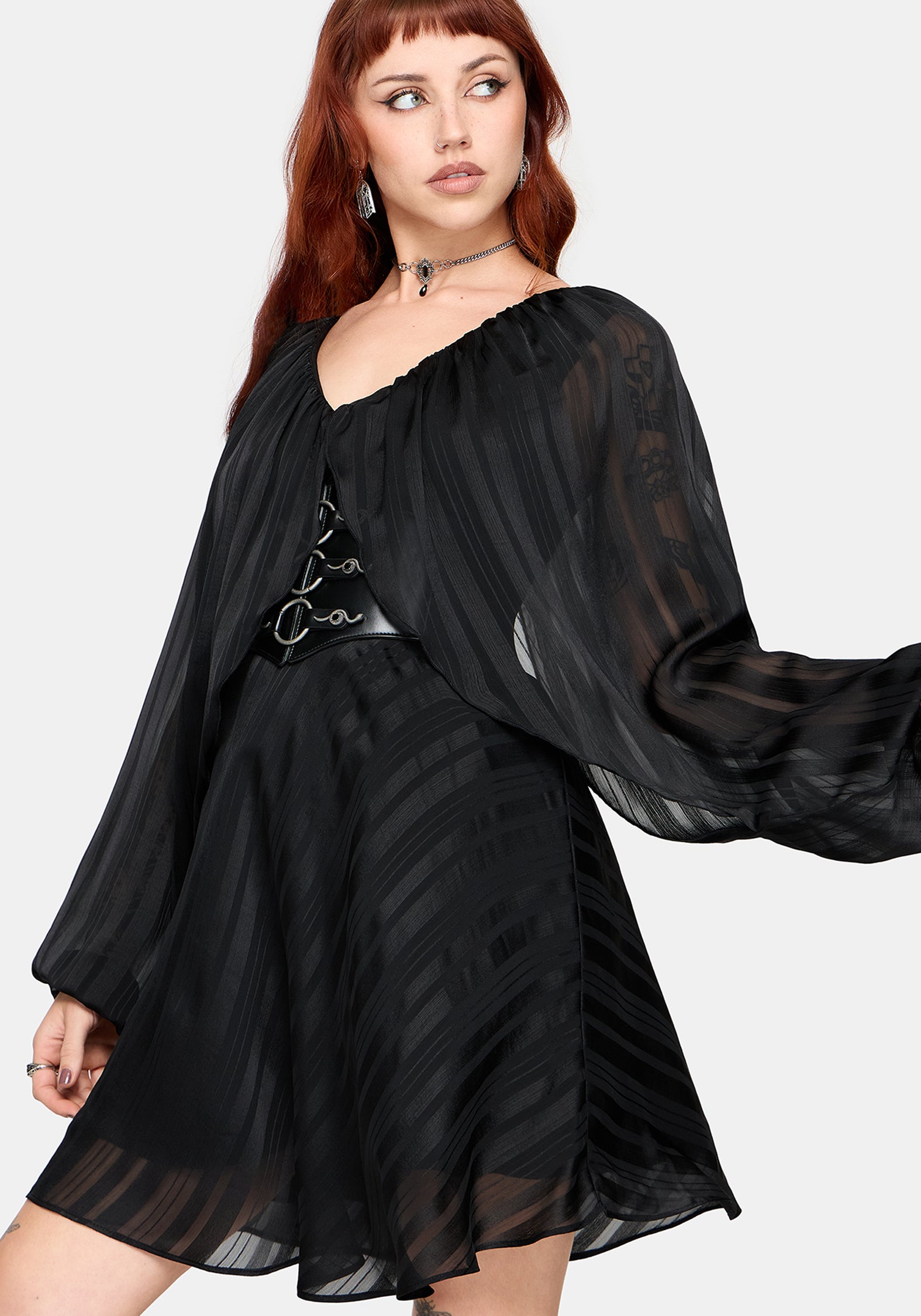 Woman wearing a black dress with sheer sleeves on a white background