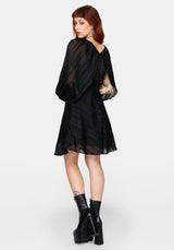 Woman wearing a black dress with sheer sleeves on a white background