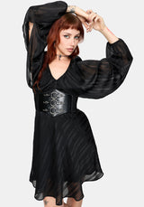 Woman wearing a black dress with a corset-style waist belt on a white background