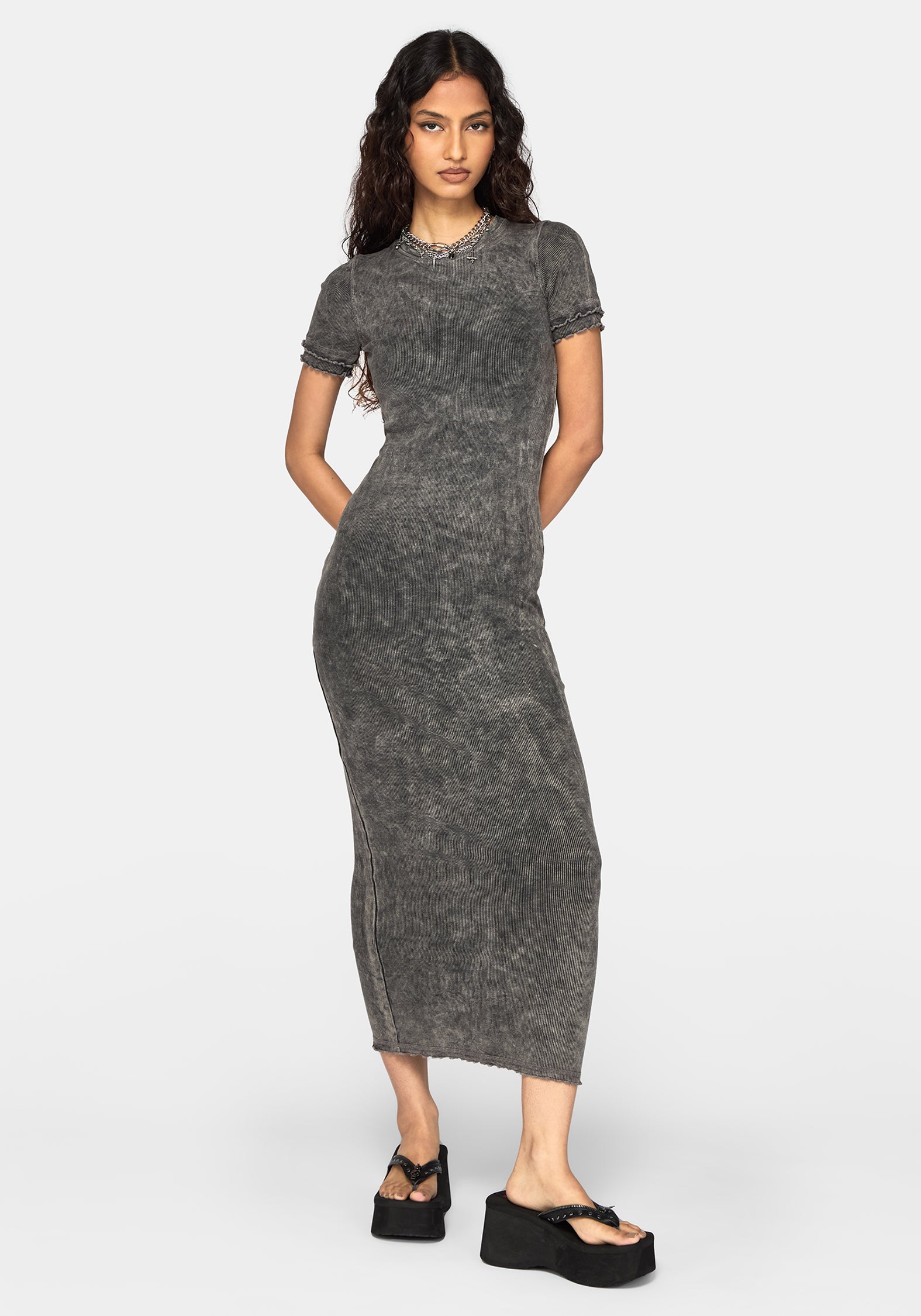 A woman modeling a short-sleeve, bodycon midi dress in a washed charcoal gray color, paired with black platform sandals, against a plain light gray background.