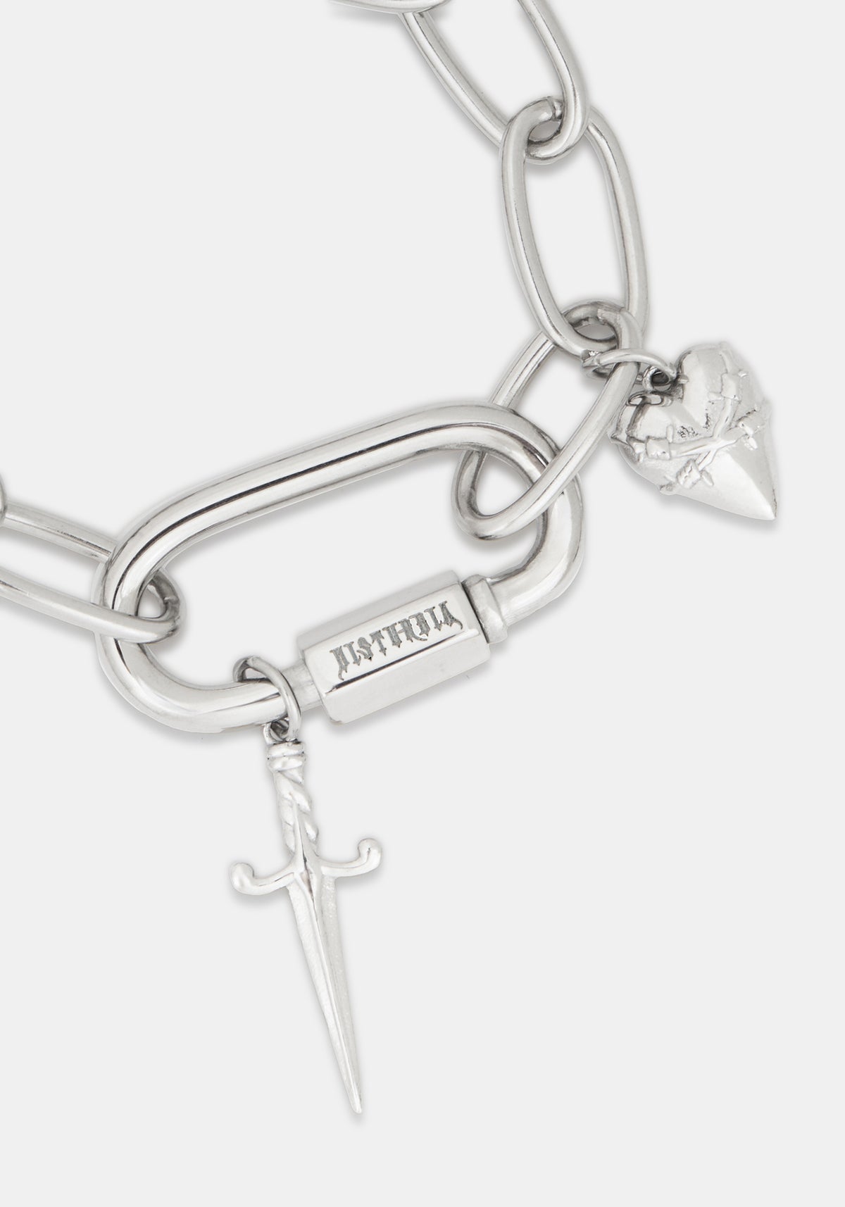 A close-up of a silver-toned chain bracelet featuring a large open-link chain, a rectangular bar engraved with 'DISTURBIA', a small dagger charm, and a heart-shaped charm with a rose engraving, on a light gray background.
