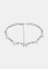 A silver-toned chain necklace featuring elongated, pointed spike links and a central extender chain, shown against a light gray background.