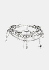 A layered silver-tone chain choker bracelet featuring chunky and delicate chains, a central ring, and dangling charms including a cross, key, and beads, shown against a light gray background.