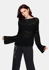 Woman wearing a black distressed jumper with long sleeves and back denim jeans on a white background