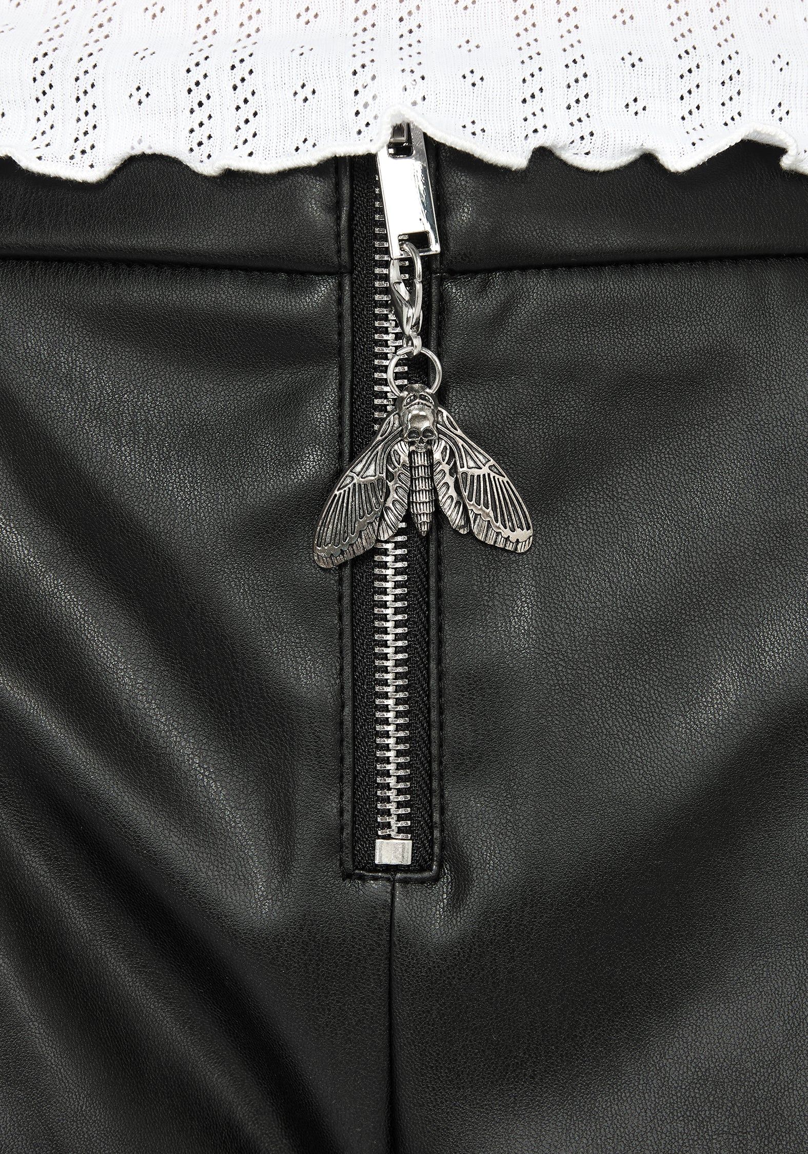 Close up of silver moth pendant on metal zip for faux leather micro shorts.