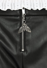 Close up of silver moth pendant on metal zip for faux leather micro shorts.