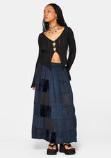 Woman wearing a black cardigan and layered navy maxi skirt on a white background