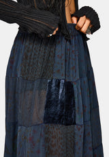 Woman wearing a black top and long navy plaid skirt on a white background