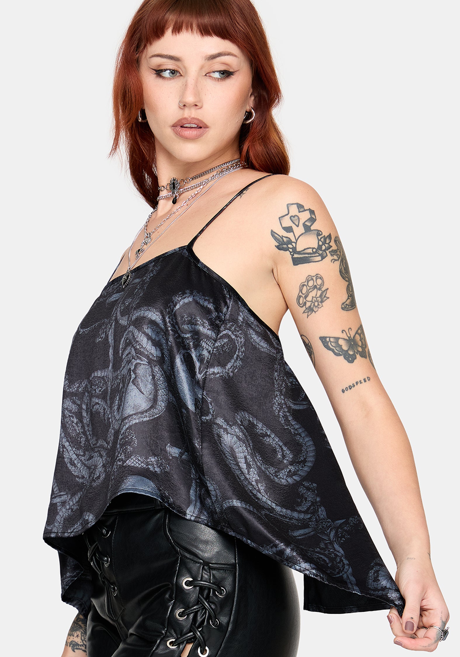 Woman wearing a black printed satin top with leather pants against a white background