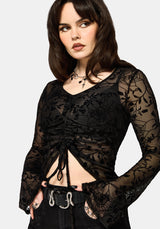 Woman wearing a black lace top with a plain background