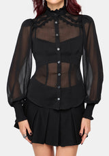 A model wearing a black sheer long-sleeve blouse with lace trim and a black pleated mini skirt, shown against a light gray studio background.