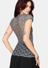 Woman wearing a gray lace top against a white background