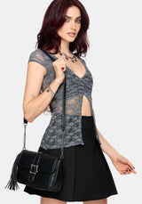 Woman wearing a gray lace top and black skirt with a black handbag on a white background