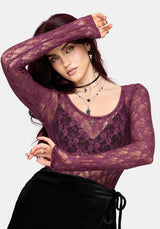 Woman wearing a sheer purple lace top with long sleeves on a white background