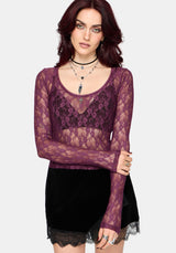 Woman wearing a sheer purple lace top with a black skirt on a white background