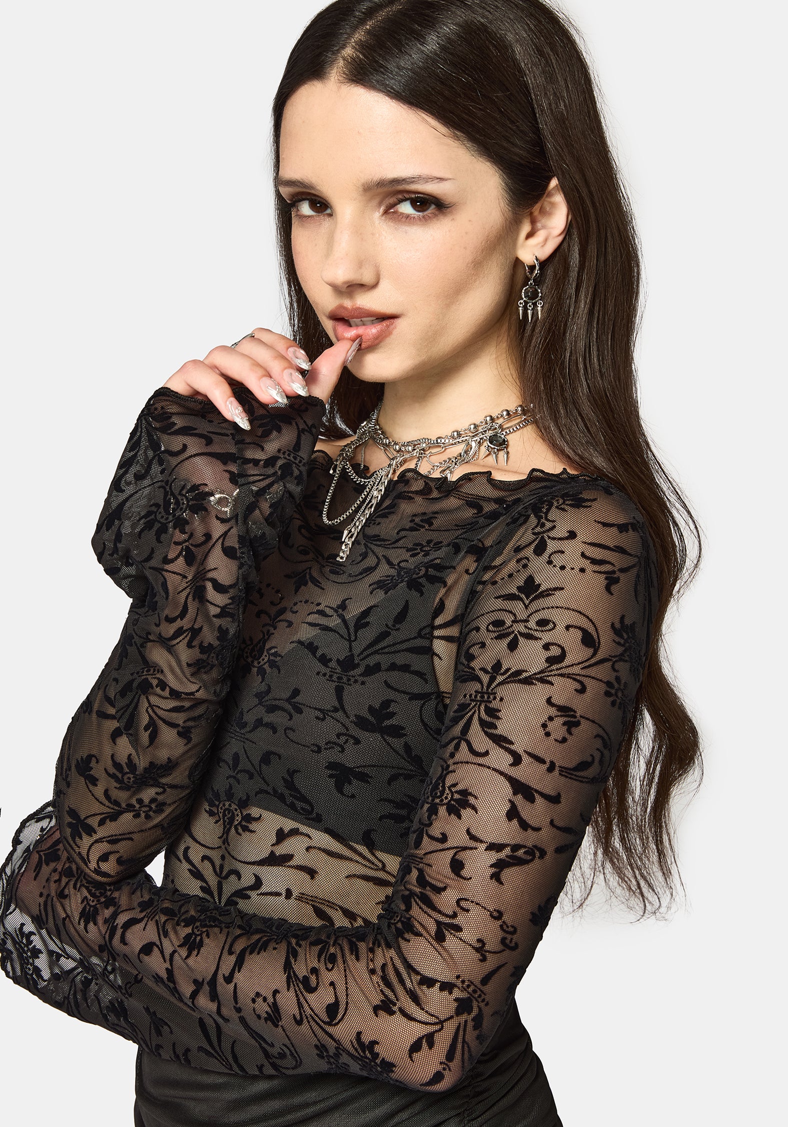 Woman wearing a black mesh long sleeve top against a white background