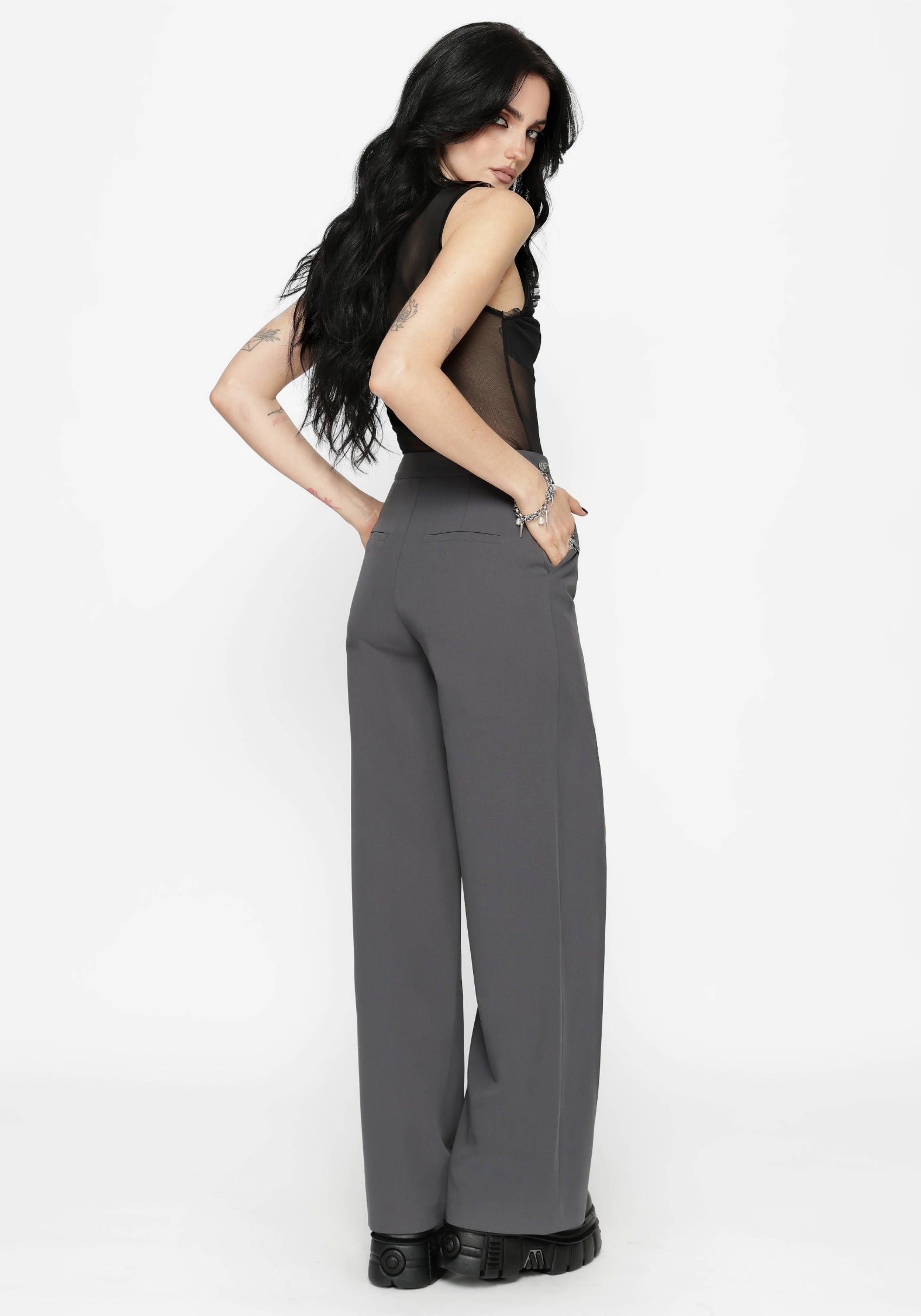 Woman wearing a black top and gray pants on a white background