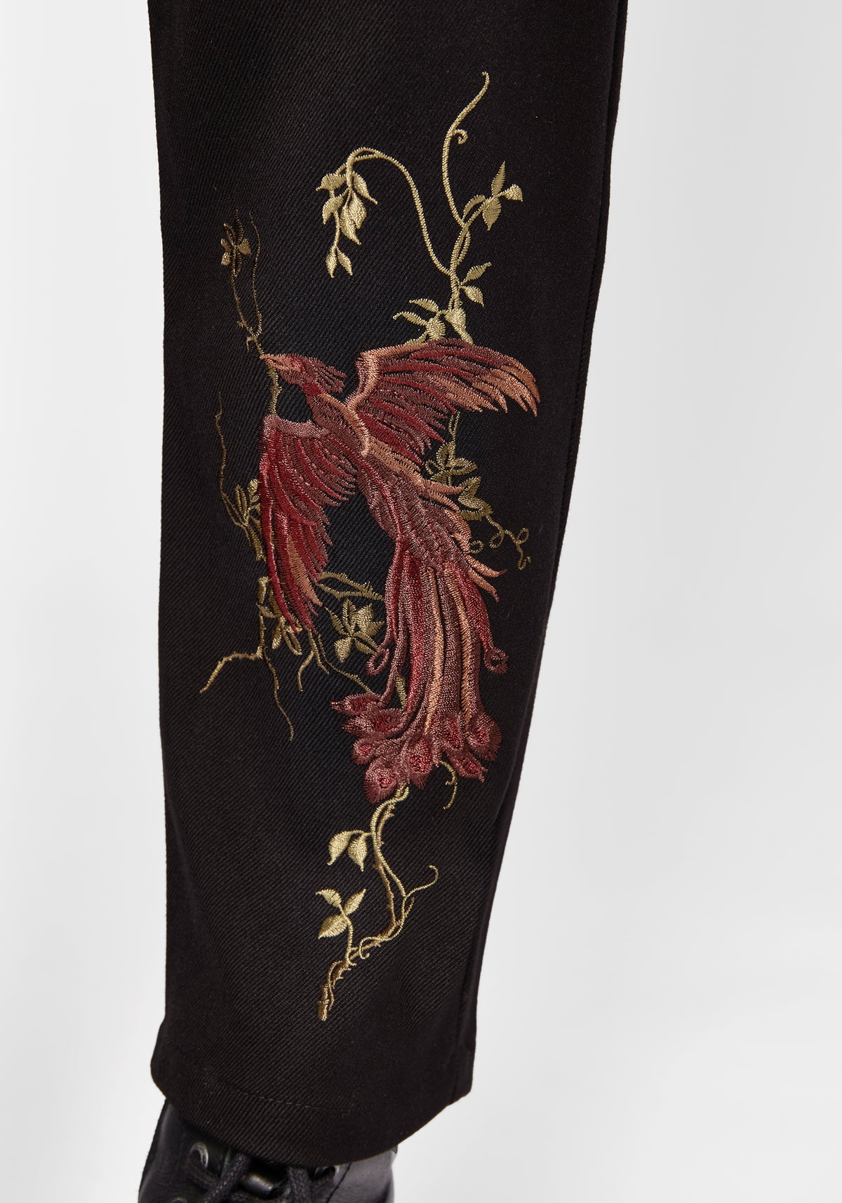 Black pants with red floral embroidery on a white background