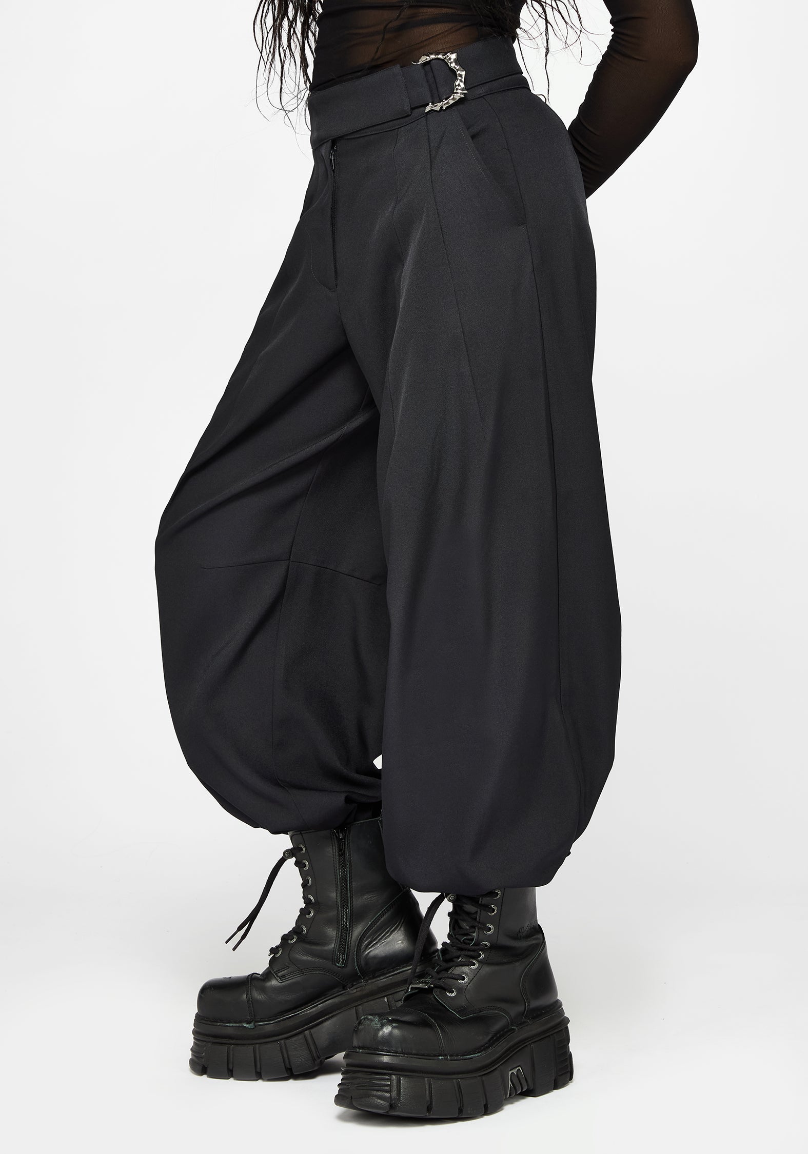 Black baggy balloon trousers with a silver buckle belt, worn by a model with black platform combat boots against a light gray background.