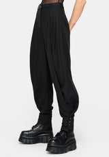 Black high-waisted balloon trousers with gathered legs and cuffed ankles, shown on a model wearing chunky black platform boots against a light gray background.