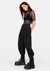 A model wearing a black sheer mesh short-sleeve crop top and matching black balloon pants with cuffs, styled with chunky black platform boots against a light gray background.