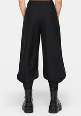 Rear view of a model wearing black wide-leg balloon pants with gathered legs and black platform ankle boots against a light gray studio background.