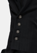 Close-up of black balloon trousers   with four decorative metallic buttons on a light gray background.
